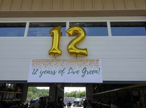 Photo of gold ballons in the shape of the number 12 above a banner that says 12 Years of Live Green